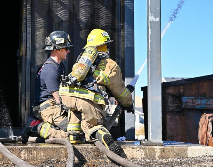 fire science student spraying hose from ground