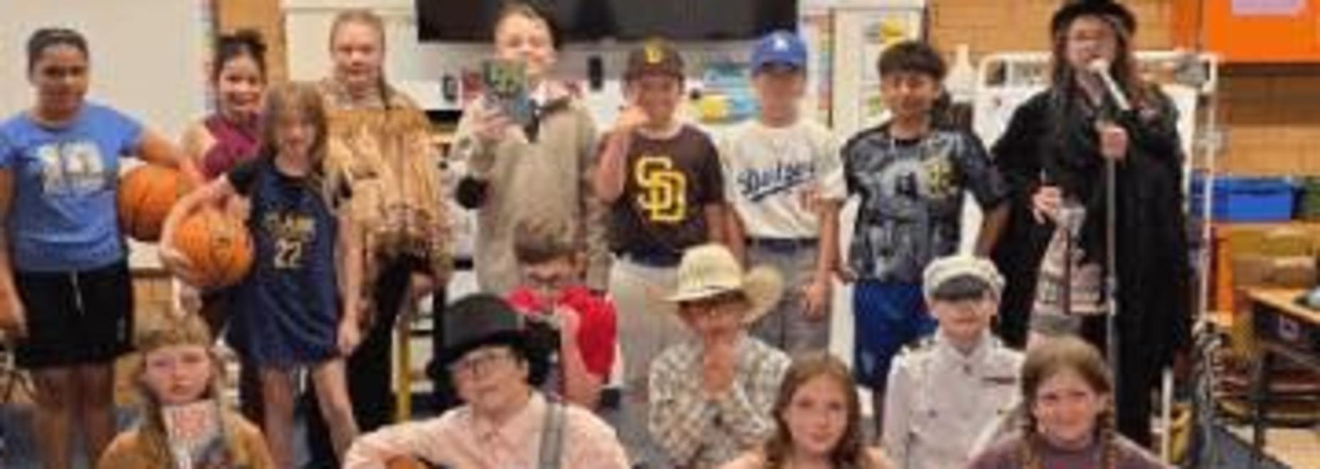 Group of children dressed in various costumes, posing together indoors.