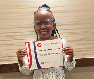 Student Elisha holding a certificate for Swimming acheivements