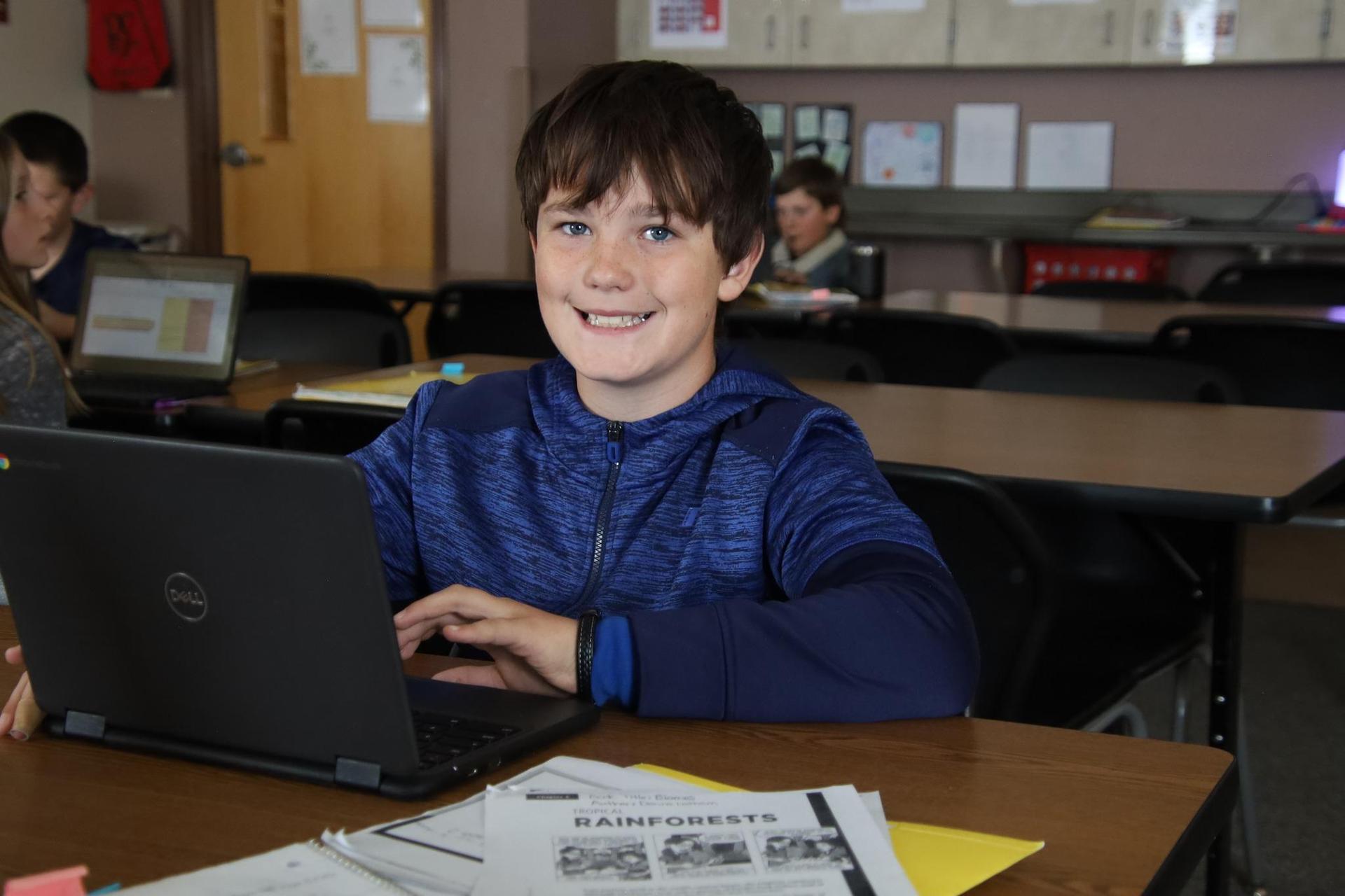 middle school boy smiling at camera in the classroom