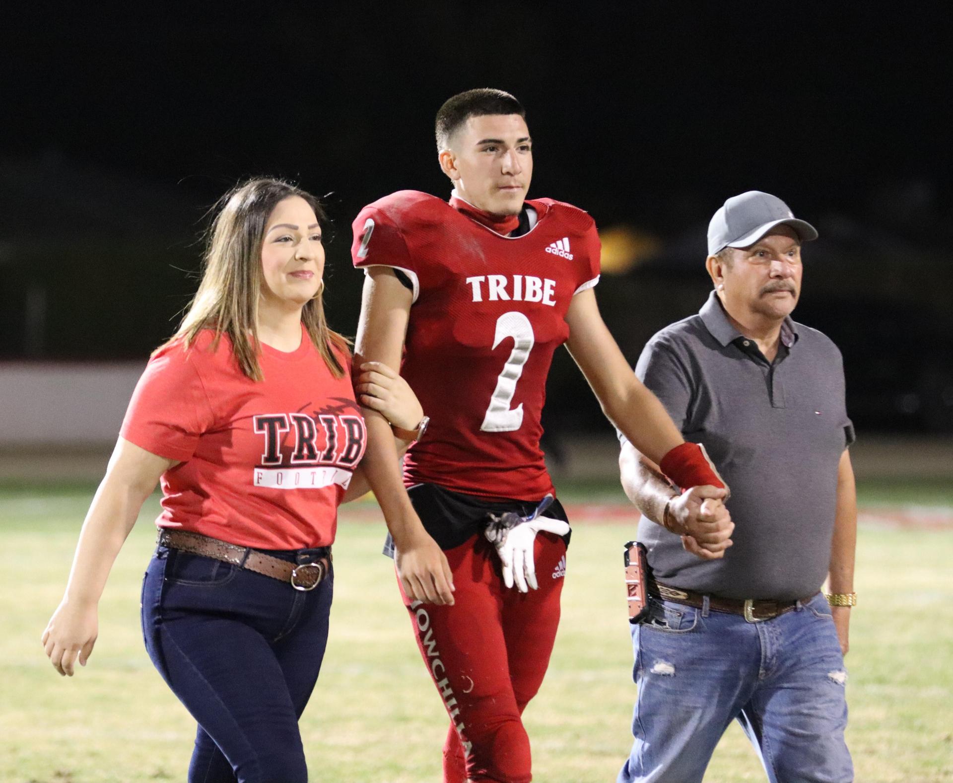 homecoming king and queen candidates walking across the field with their escorts