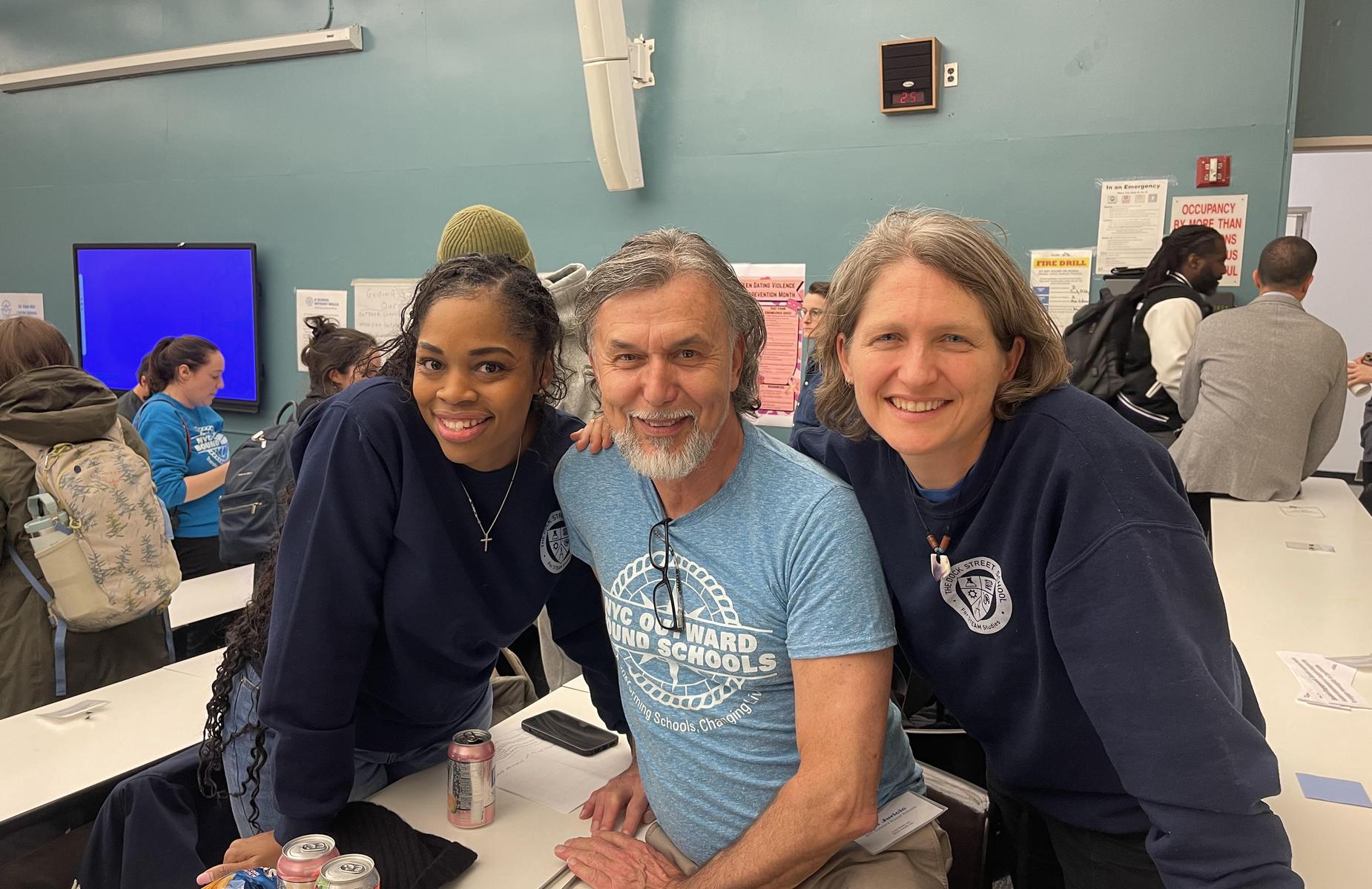 Three people posing together in a classroom setting.