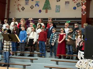 Group of students wearing sunglasses perform on stage with enthusiasm.