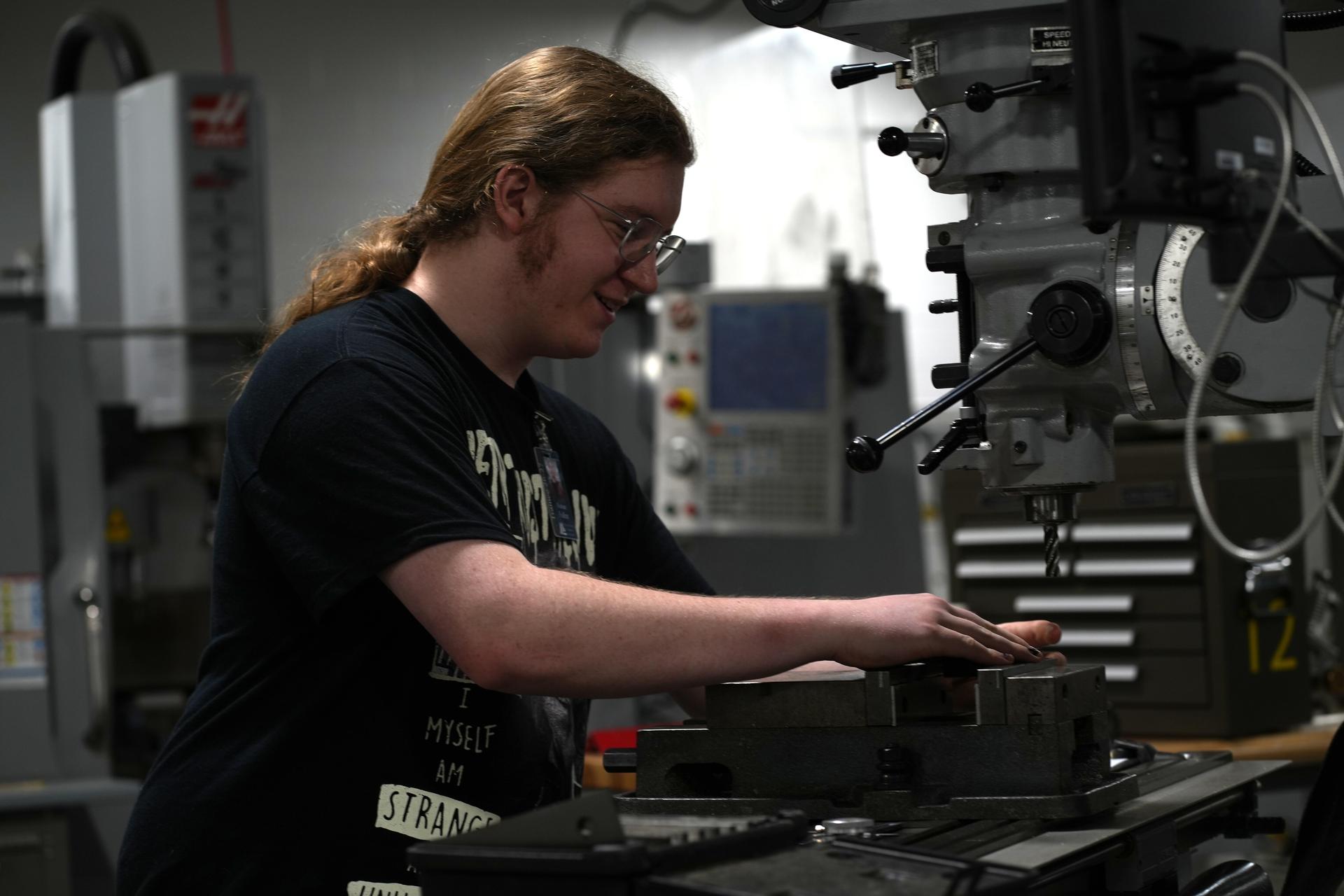Young man operating a milling machine in a workshop.