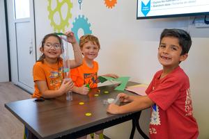 Three students posing with their beanstock project in the Mobile STEM Lab.