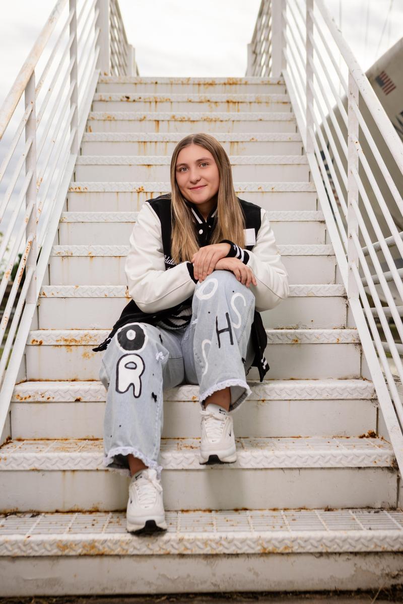 Woods sitting on stairs wearing letterman's jacket 2026