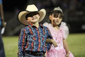 Two kids pose, one in a cowboy hat and the other in a pink dress.