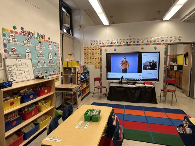 Classroom featuring colorful walls, a screen, and organized learning materials.