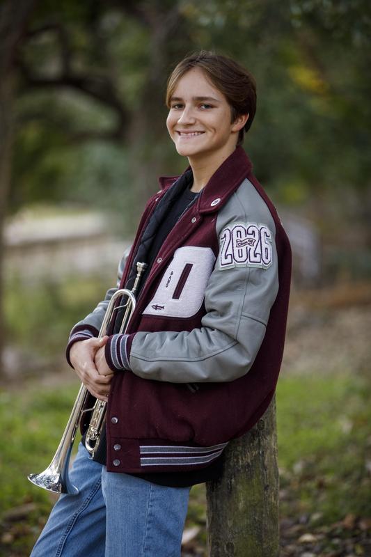 Davenport High School senior Caleb Atkins wearing his varsity jacket and holding his trumpet.