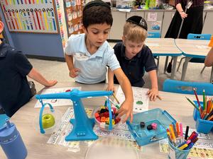 Two Kindergarten boys check how much an apple weighs.
