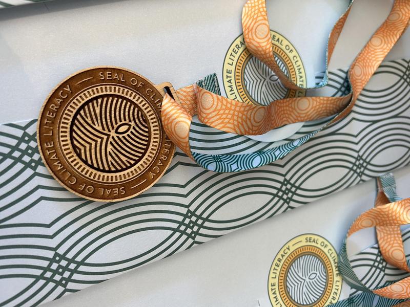 Seal of Climate Literacy medal sitting on a certificate