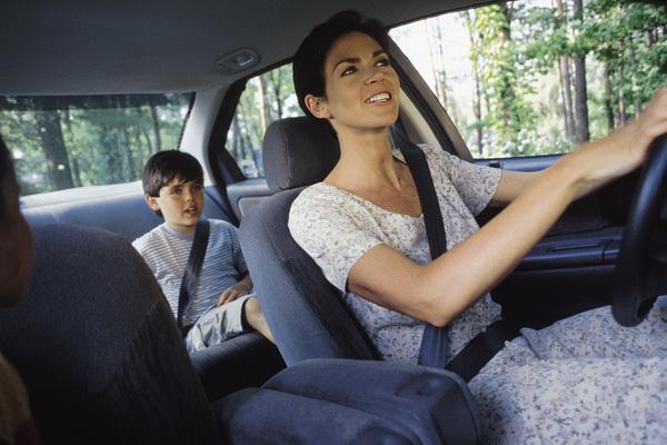 parent in car driving child who is in the back seat