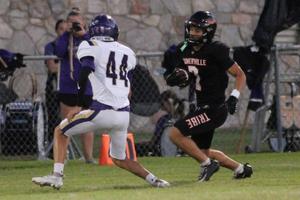 Football player runs with the ball while being pursued by an opponent.