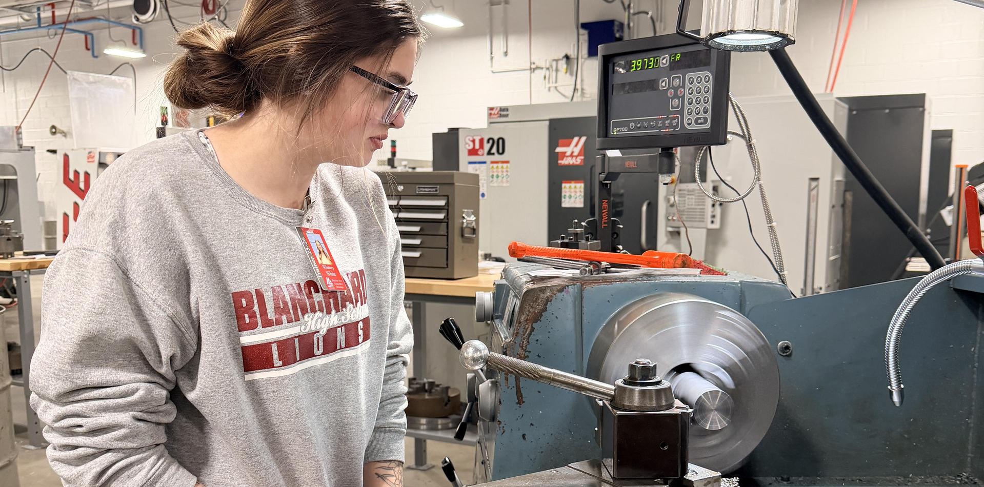 A person operating a lathe machine in a workshop.