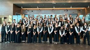 Group photo of band in uniform in front of a trophy case