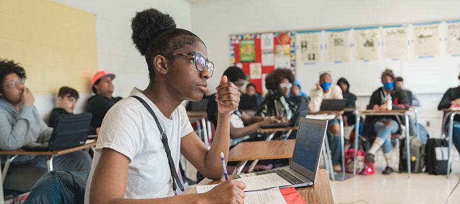 student writing in notebook in classroom