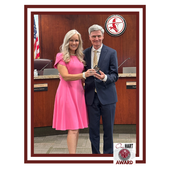 A man and woman posing for a photo in a board room settin.