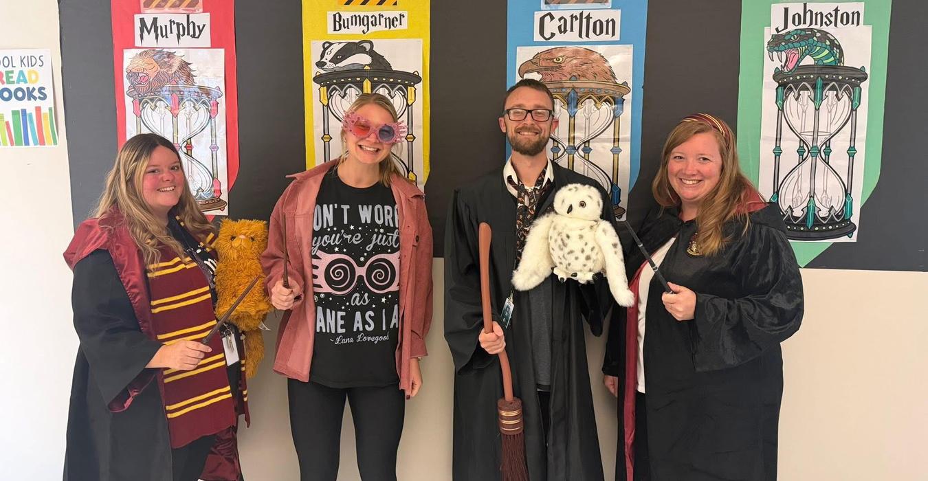 Four adults dressed as characters from a wizarding story with props.
