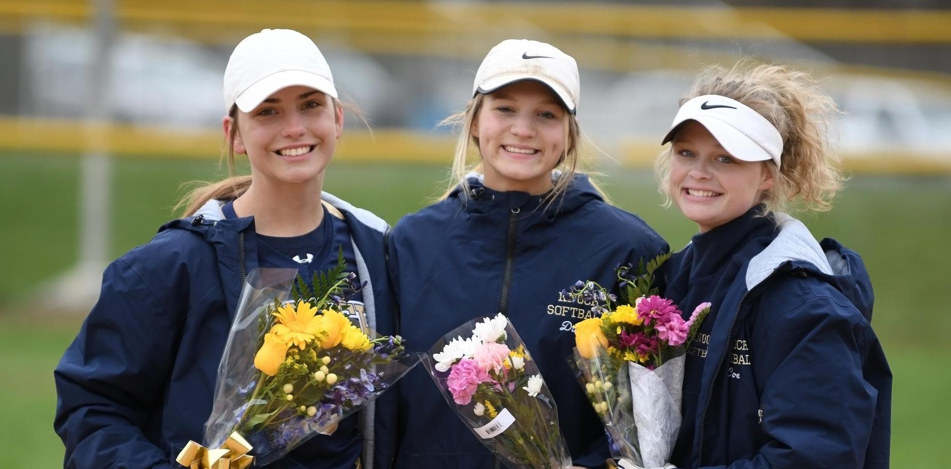 3 senior players in warm ups holding flowers