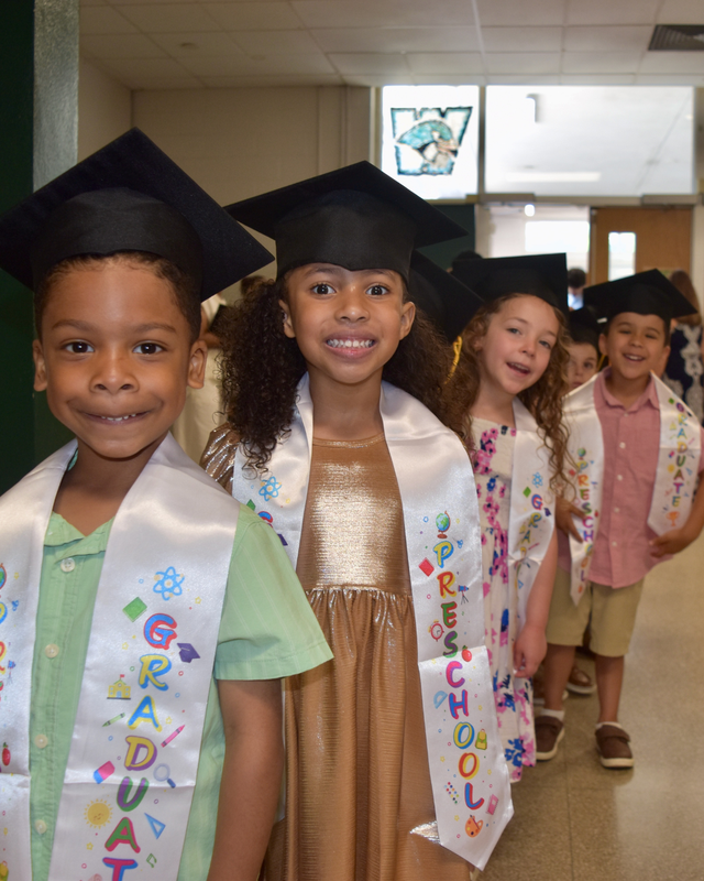 Graduates line up in caps and sashes, full of smiles