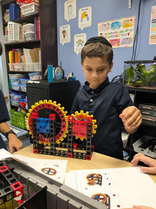 A student tests how the size of a gear impacts how much a motor can lift.