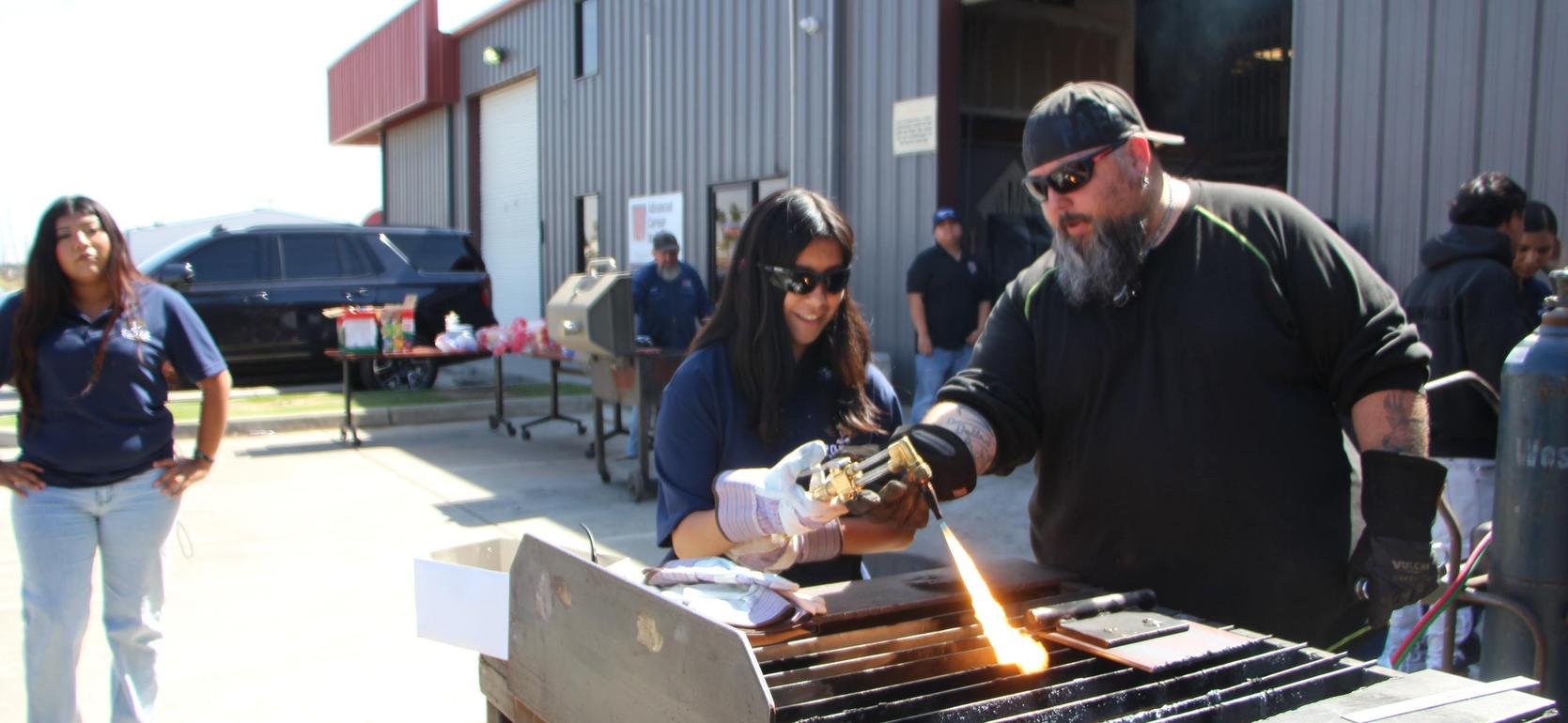 Two people working together at a welding station outdoors.