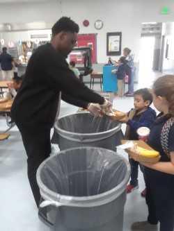 Adult helping a student separate recyclables