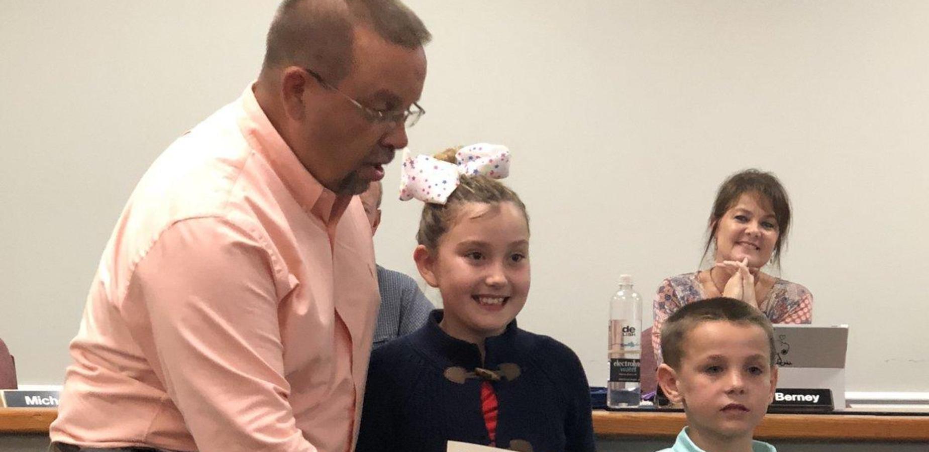 Students receiving attendance award at the school board meeting.