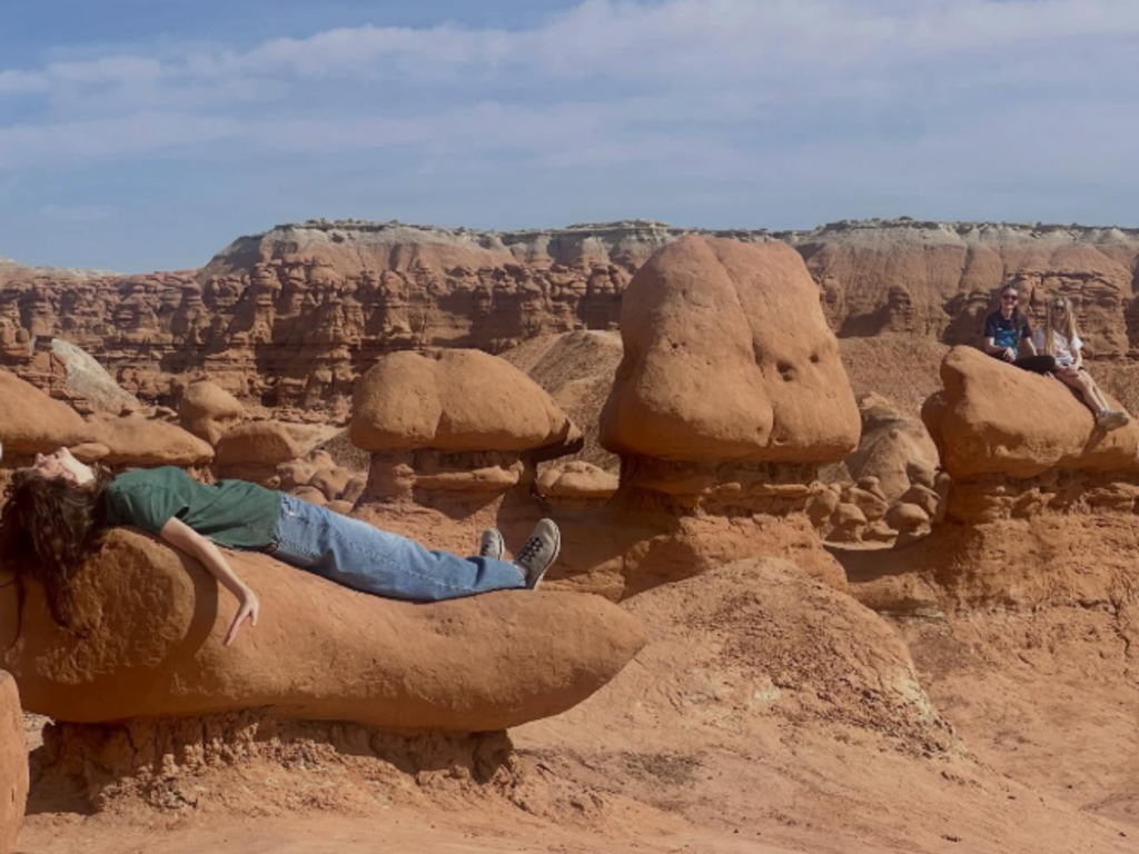 Student lying on red boulders.