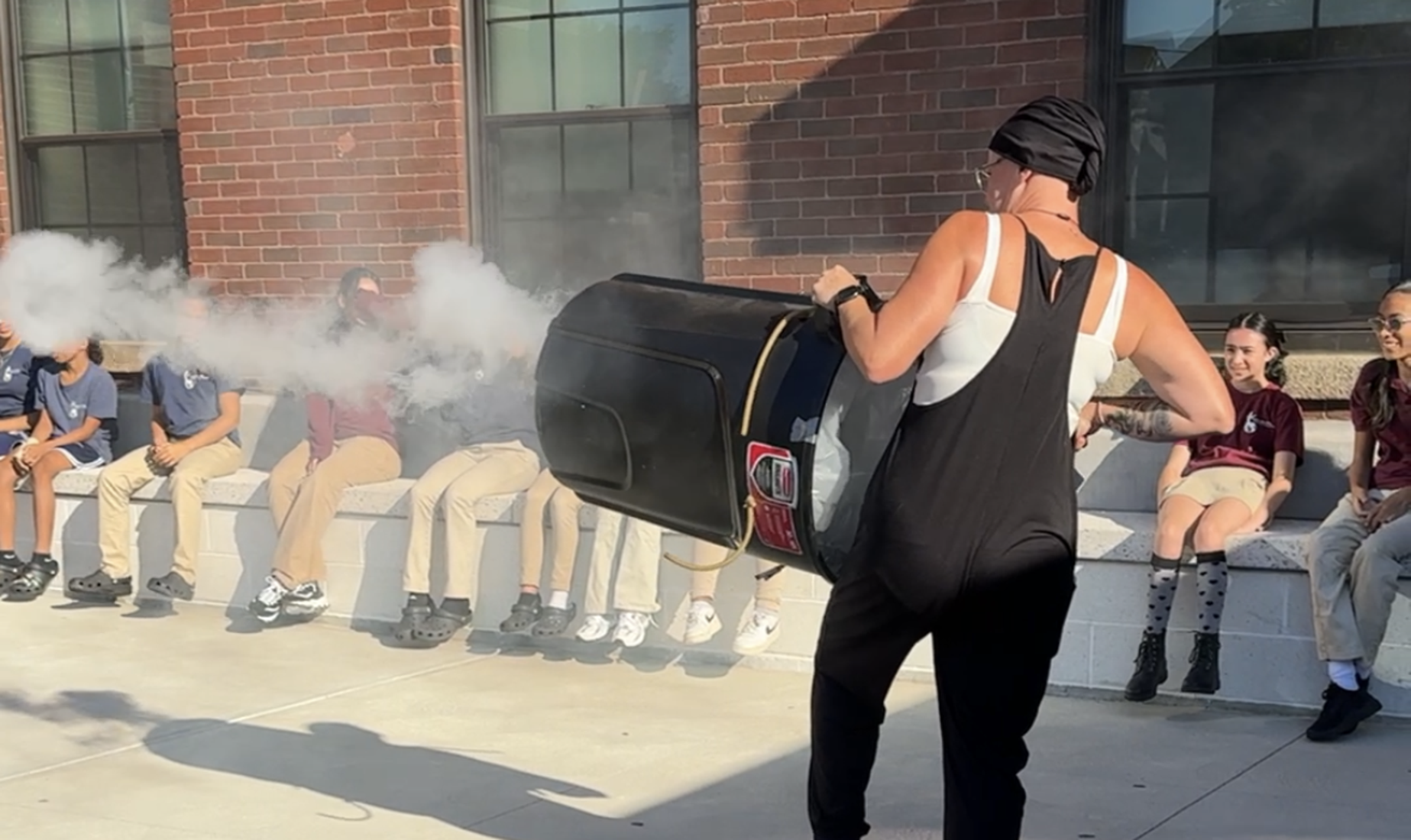 Teacher shooting cannon while students look on.