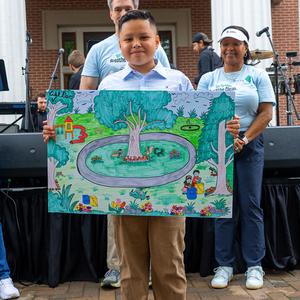 Student posing for picture with their Earth Day poster
