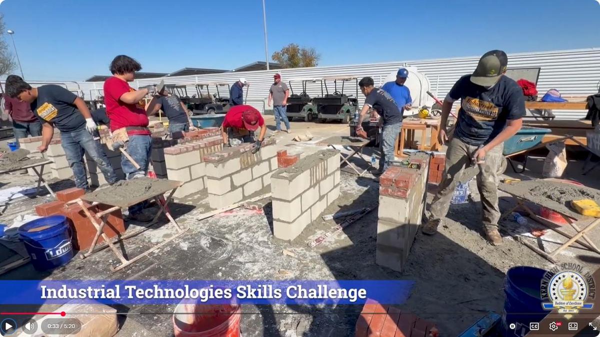 Students actively building brick walls at a skills competition outdoors.