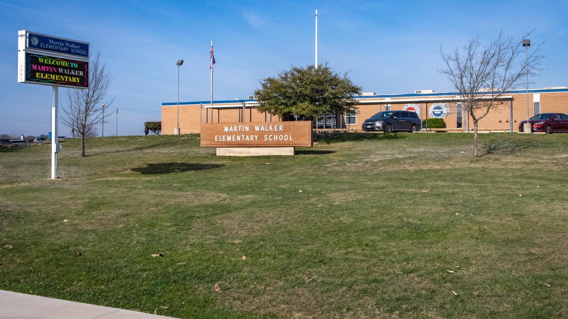 Exterior view of Martin Walker Elementary School with flags and lawns in front.