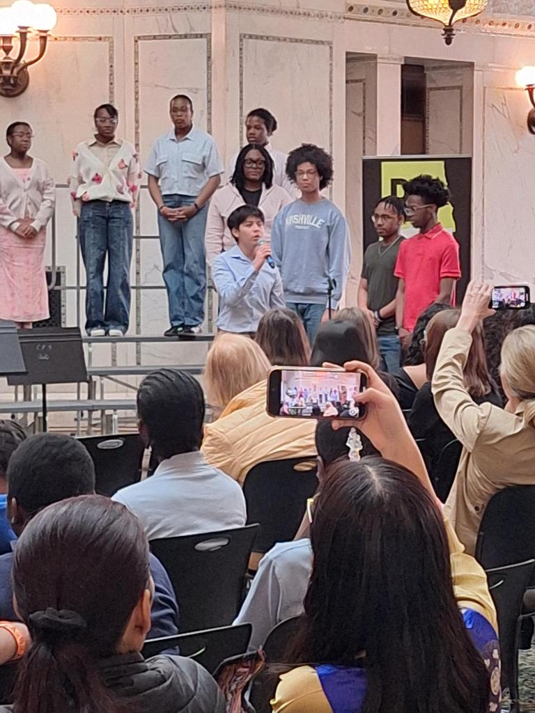 Choir singing in front of seated crowd.
