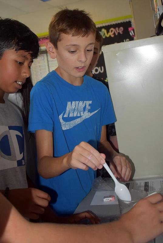 Children participating in a classroom science activity with materials and instructions.