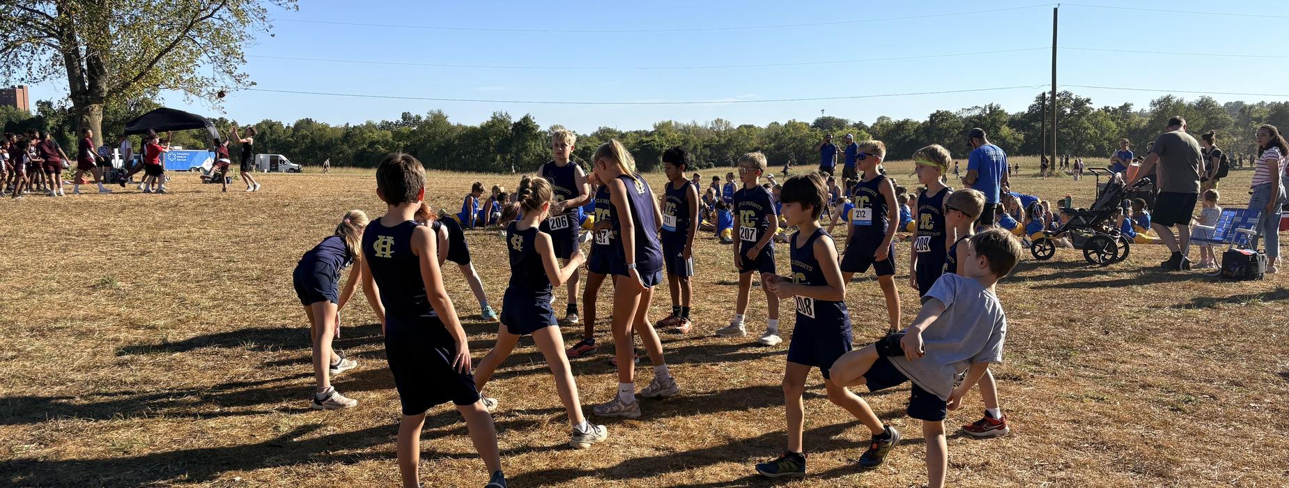 Young athletes stretching and warming up on a grassy field before a race.