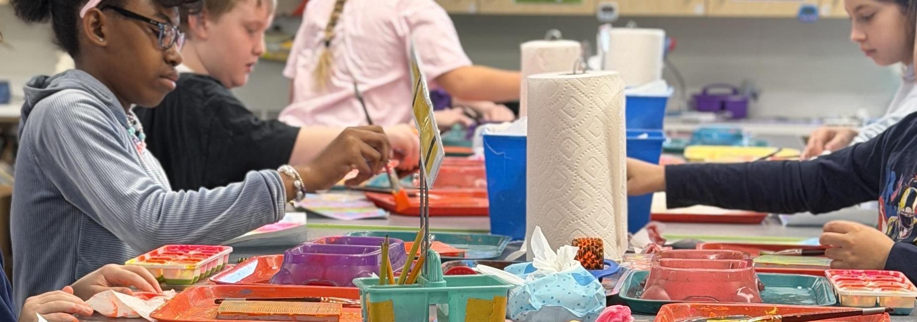Children engaged in painting at a colorful art table.