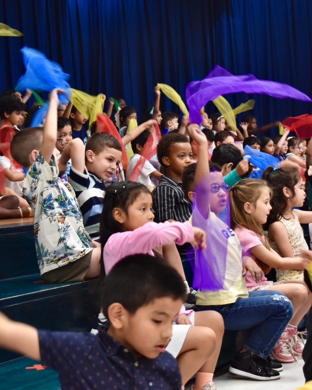 Kids wave scarves overhead while singing