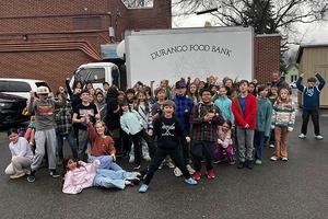 A large group of fifth-grade students stand in front of a box truck that reads Durango Food Bank.