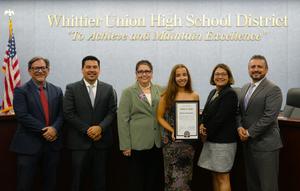Whittier Union High School District student Marle Schaefer stands with District Board members while holding her Award of Merit certificate during a recognition ceremony in the Board of Trustees meeting room.