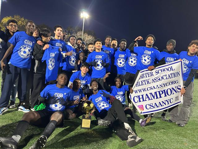 Group of soccer players in blue shirts celebrating a championship win.