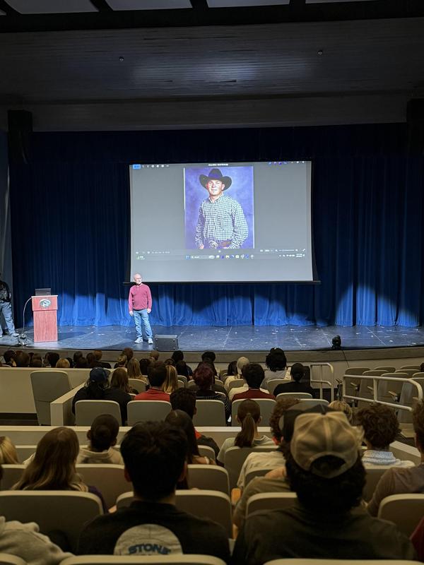 photo of a man talking to a large group of students