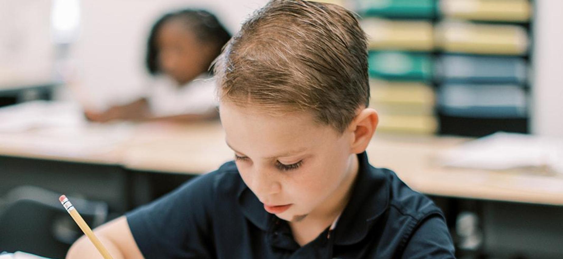 Student focused on writing at his desk