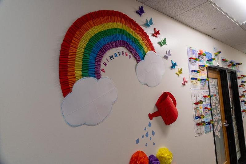 A decoration on the wall at Arco Iris Spanish Immersion school of a rainbow and butterflies. Text says “primavera”.