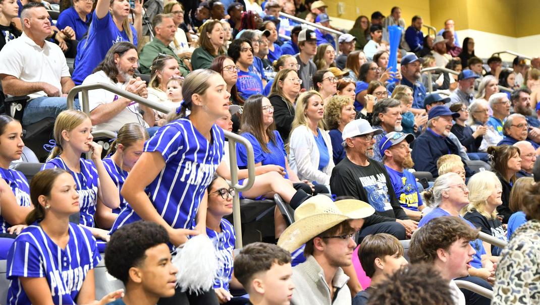 A crowd of enthusiastic fans in a sports arena cheering for their team.