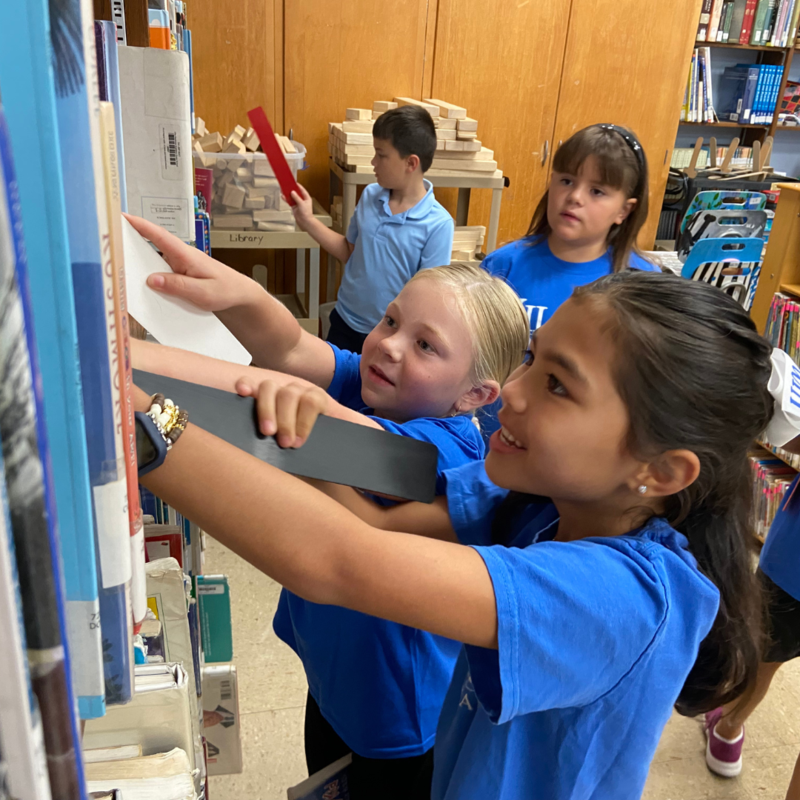 Smiling students choose books from the library.