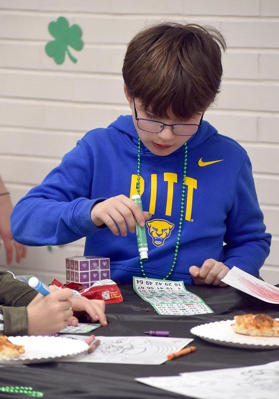 Boy in blue shirt marking bingo cards with a marker.