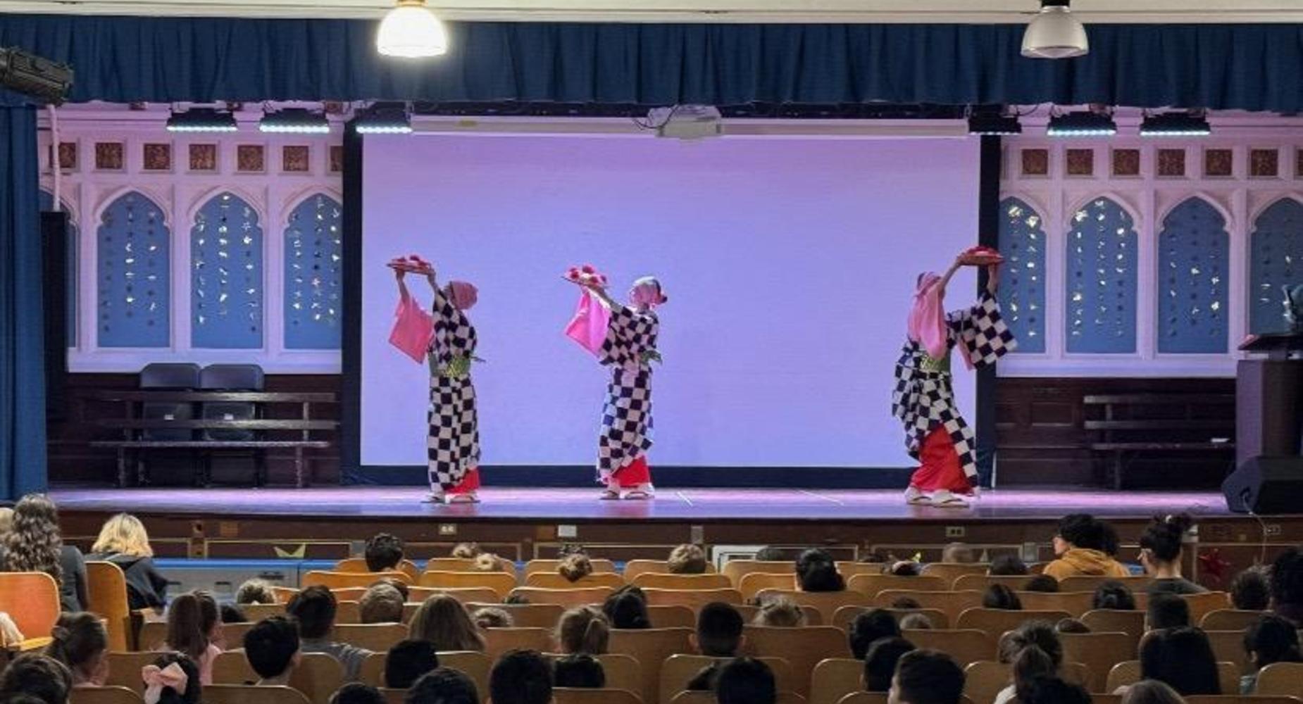 3 dancers in black and white check with pink sleeves and bottom of skirt