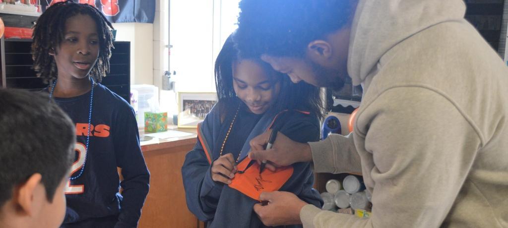Football player autographs a student's sweatshirt