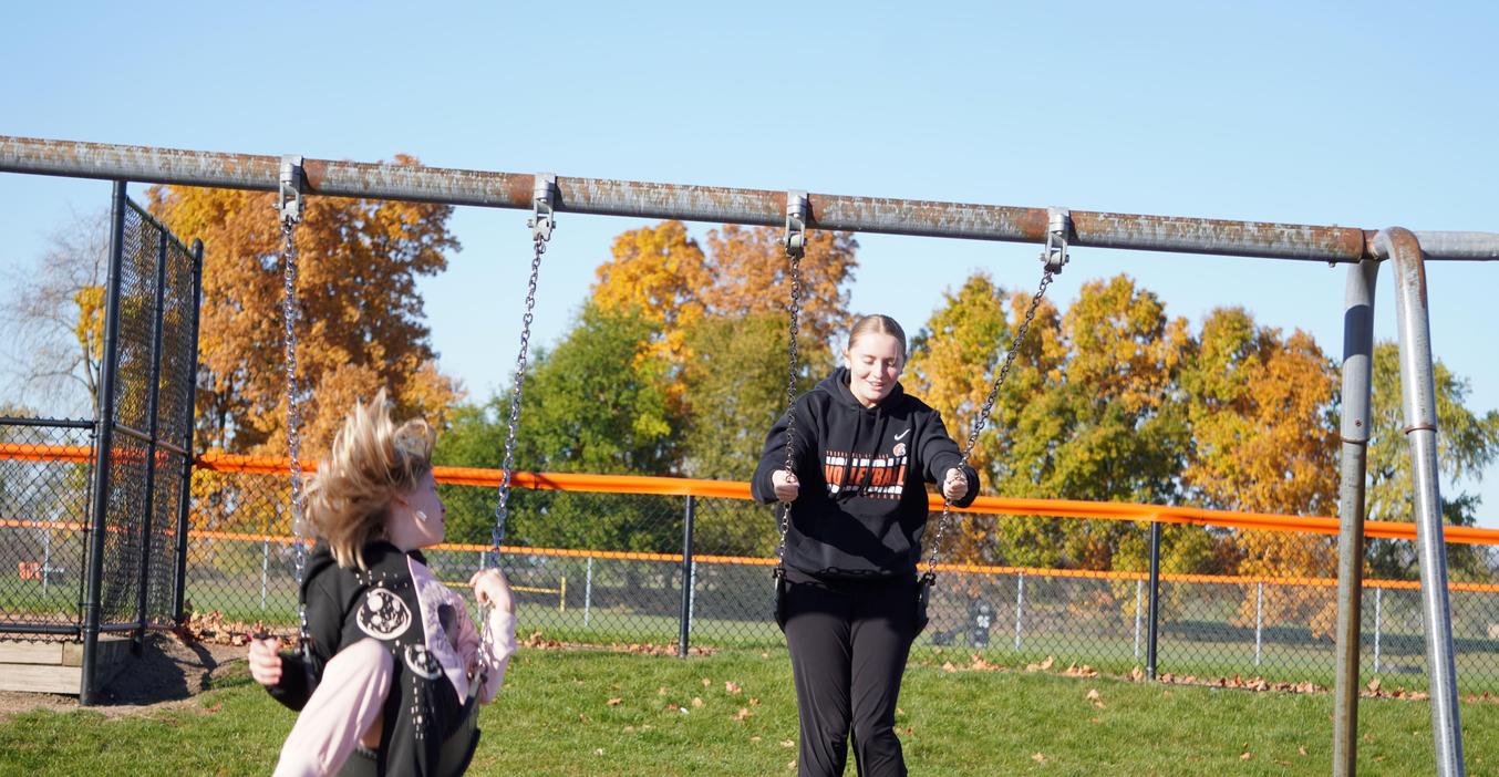 A high school student swings with a Page Elementary student.
